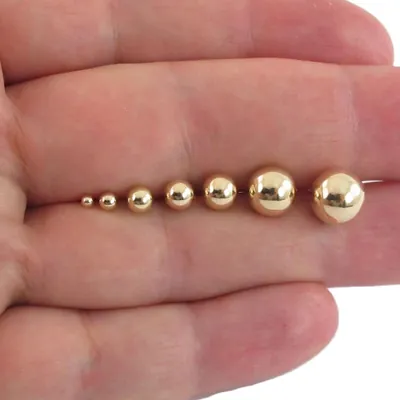 14k yellow gold ball stud earrings in seven sizes along two fingers